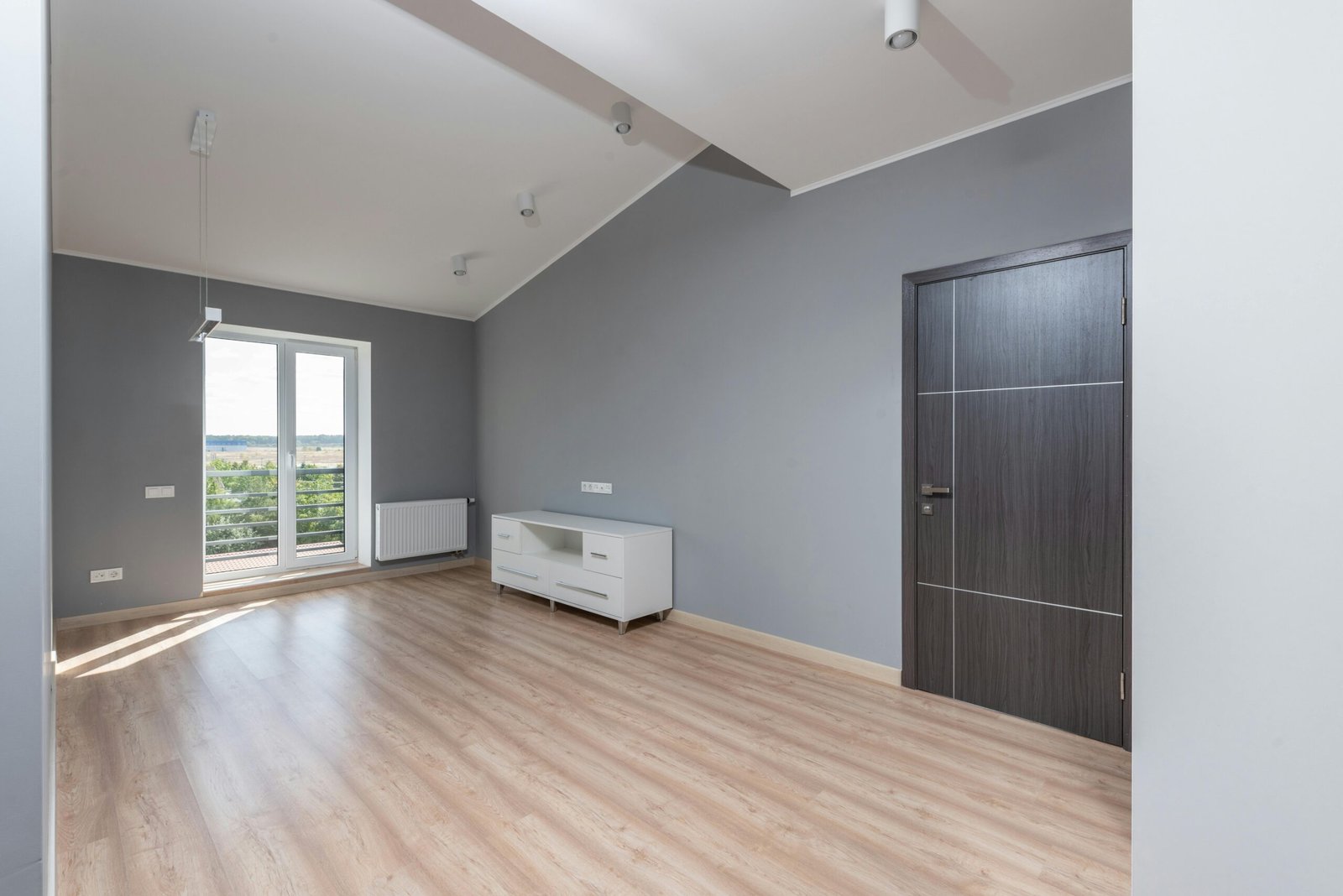 Inicio Bright and empty modern room with hardwood floors and large window view.